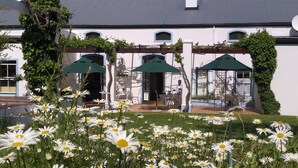 Un bâtiment blanc doté d’un patio couvert, avec des espaces de détente en plein air et des parasols.