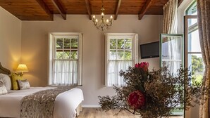 Une chambre à coucher avec un lit, une lampe, une télévision et une fenêtre avec des rideaux.
