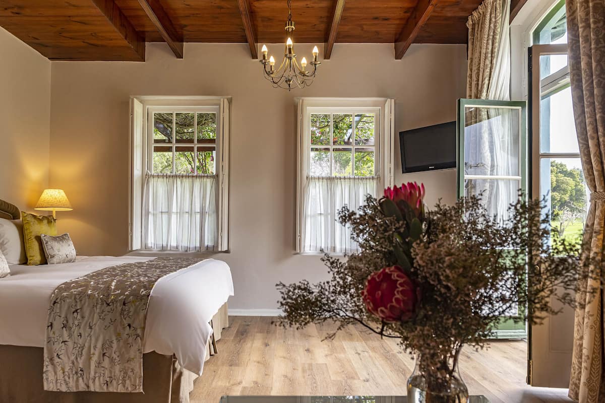 A bedroom with a bed, a lamp, a TV, and a window with curtains.