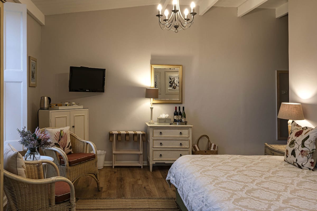 A bedroom with a bed, a dresser, a television, a mirror, and a chandelier.