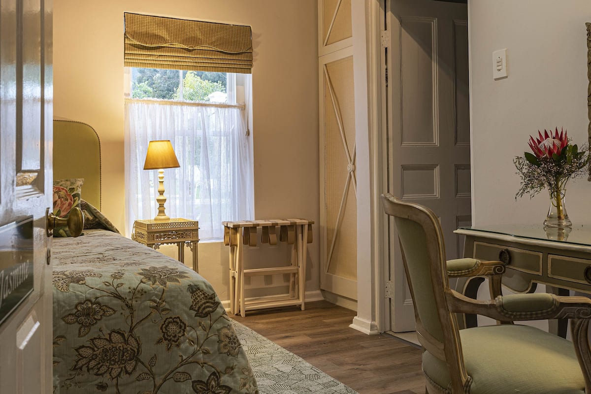 A bedroom with a bed, a chair, a desk, and a window with curtains.