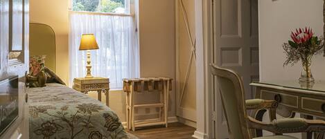A bedroom with a bed, a chair, a desk, and a window with curtains.