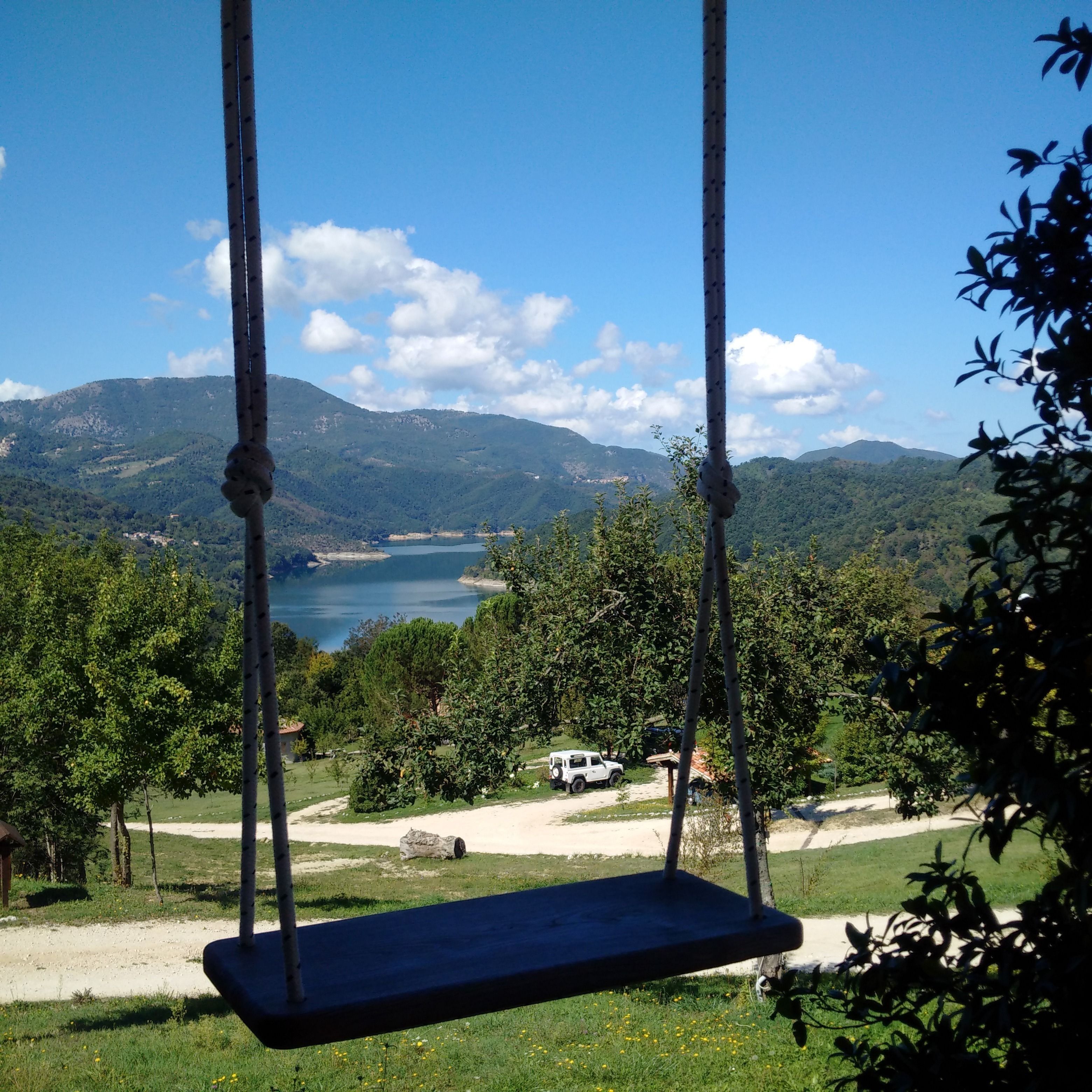Une balançoire donnant sur un lac, avec des montagnes en arrière-plan.