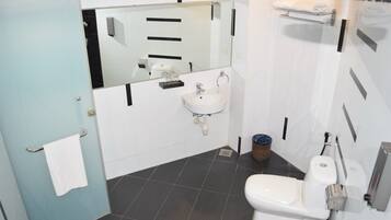 Un baño con lavamanos blanco, espejo, inodoro y toallero.