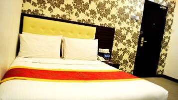 A hotel room with a bed, a nightstand, a telephone, and a door.