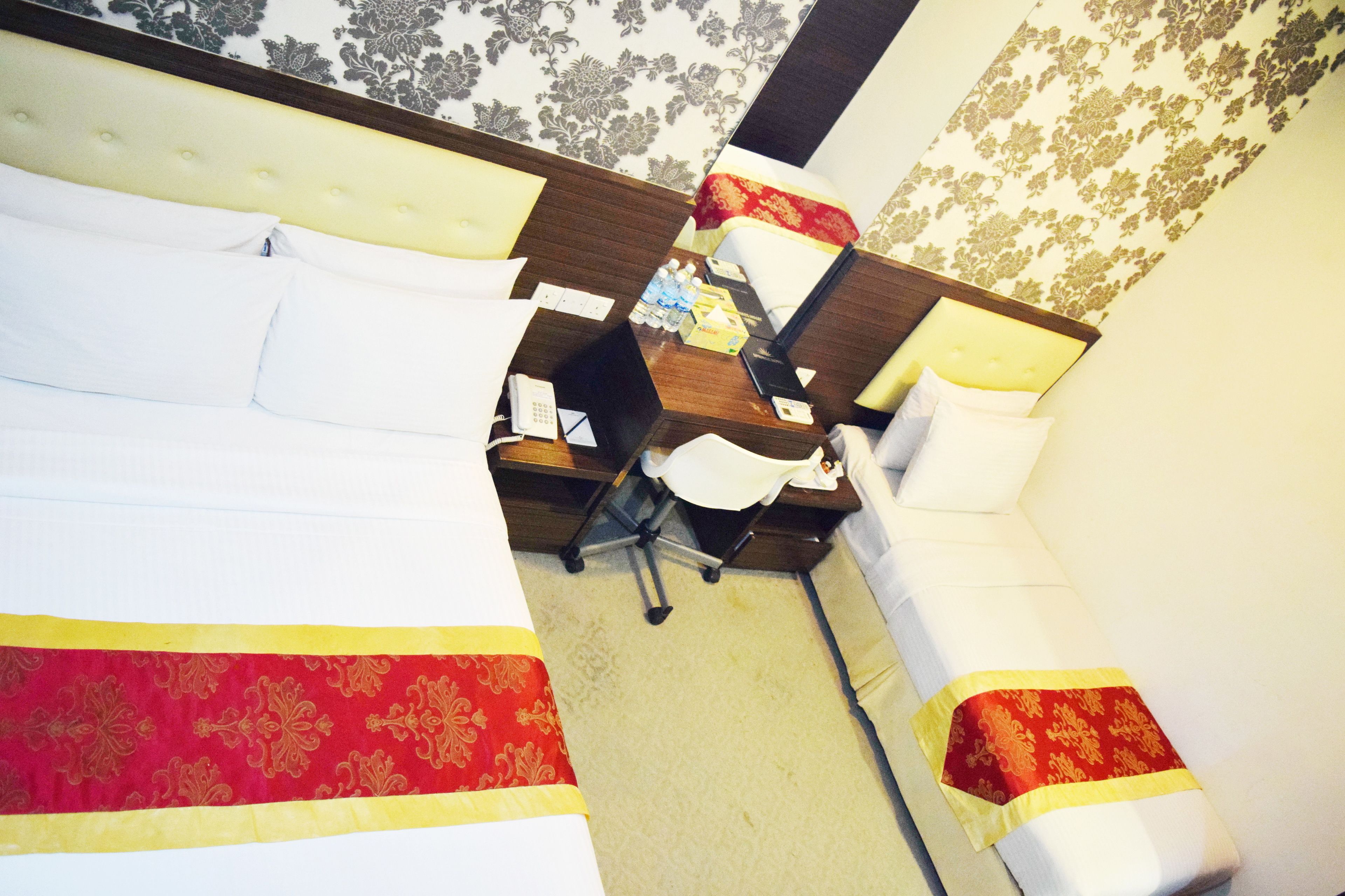 Quarto de hotel com duas camas, uma mesa e uma cadeira.