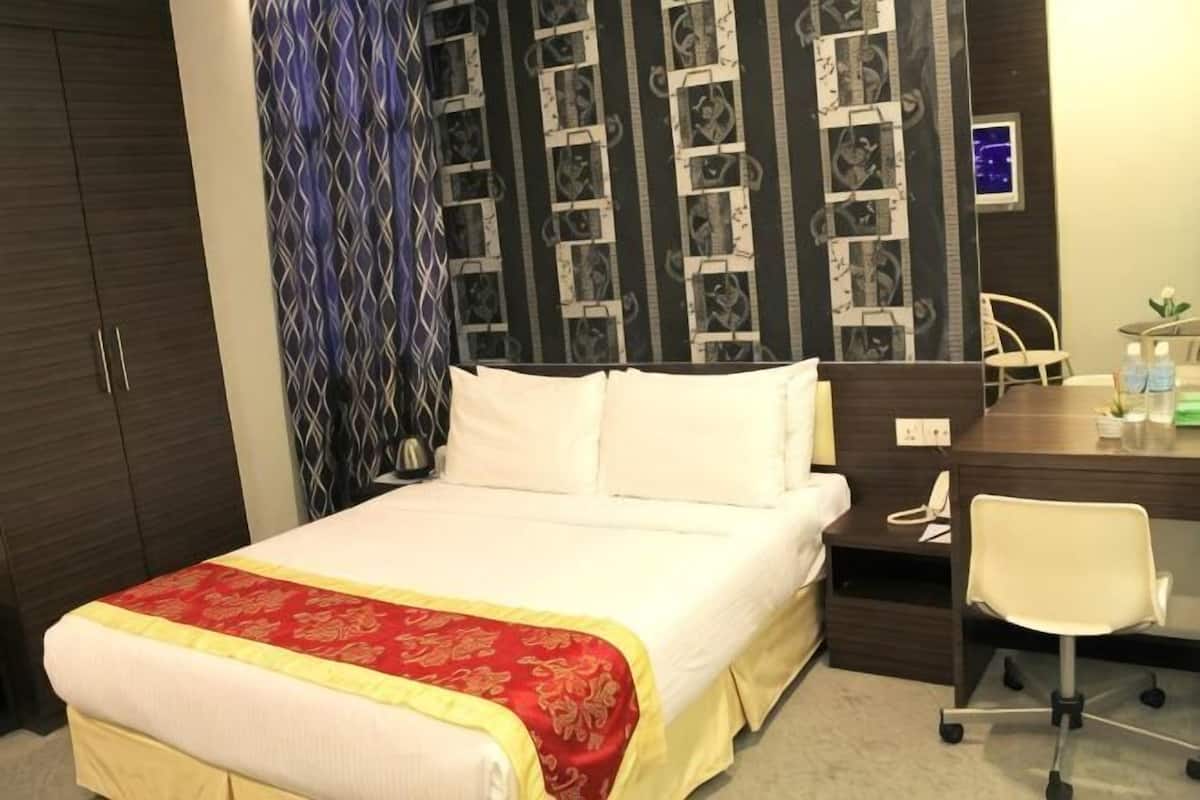 A hotel room with a bed, a desk, a chair, and a wardrobe.