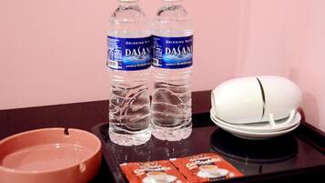 En bricka med två flaskor Dasani-vatten, en vit askkopp, en rosa askkopp och ett paket snabbkaffeblandning.
