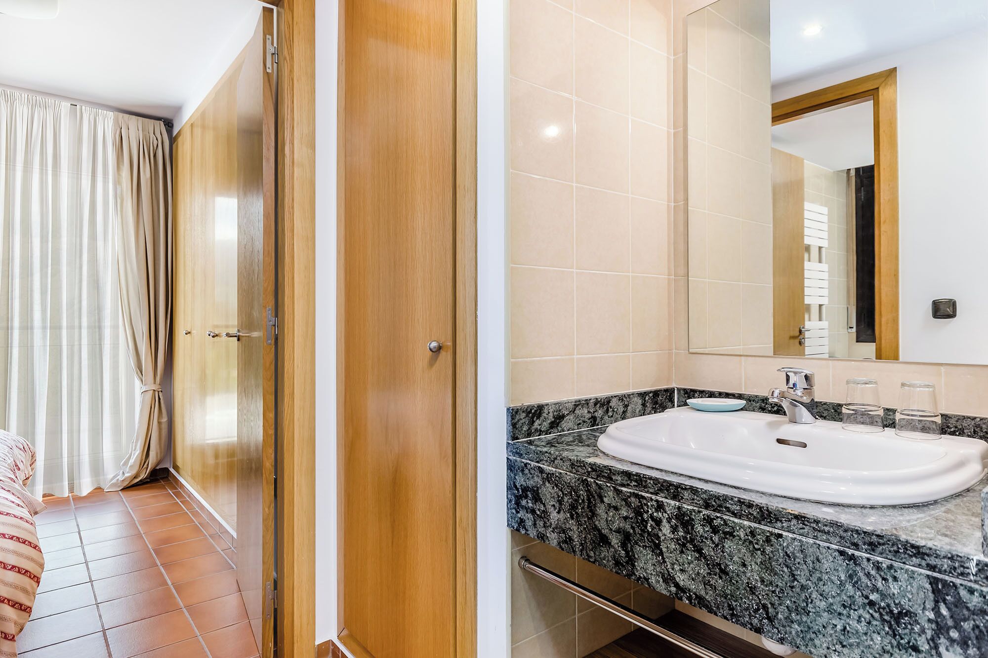 Un baño de hotel con lavamanos de mármol, un espejo y zona de ducha.