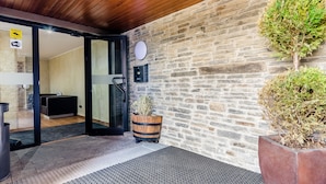 A modern entrance with a stone wall, wooden ceiling, and a small potted plant.