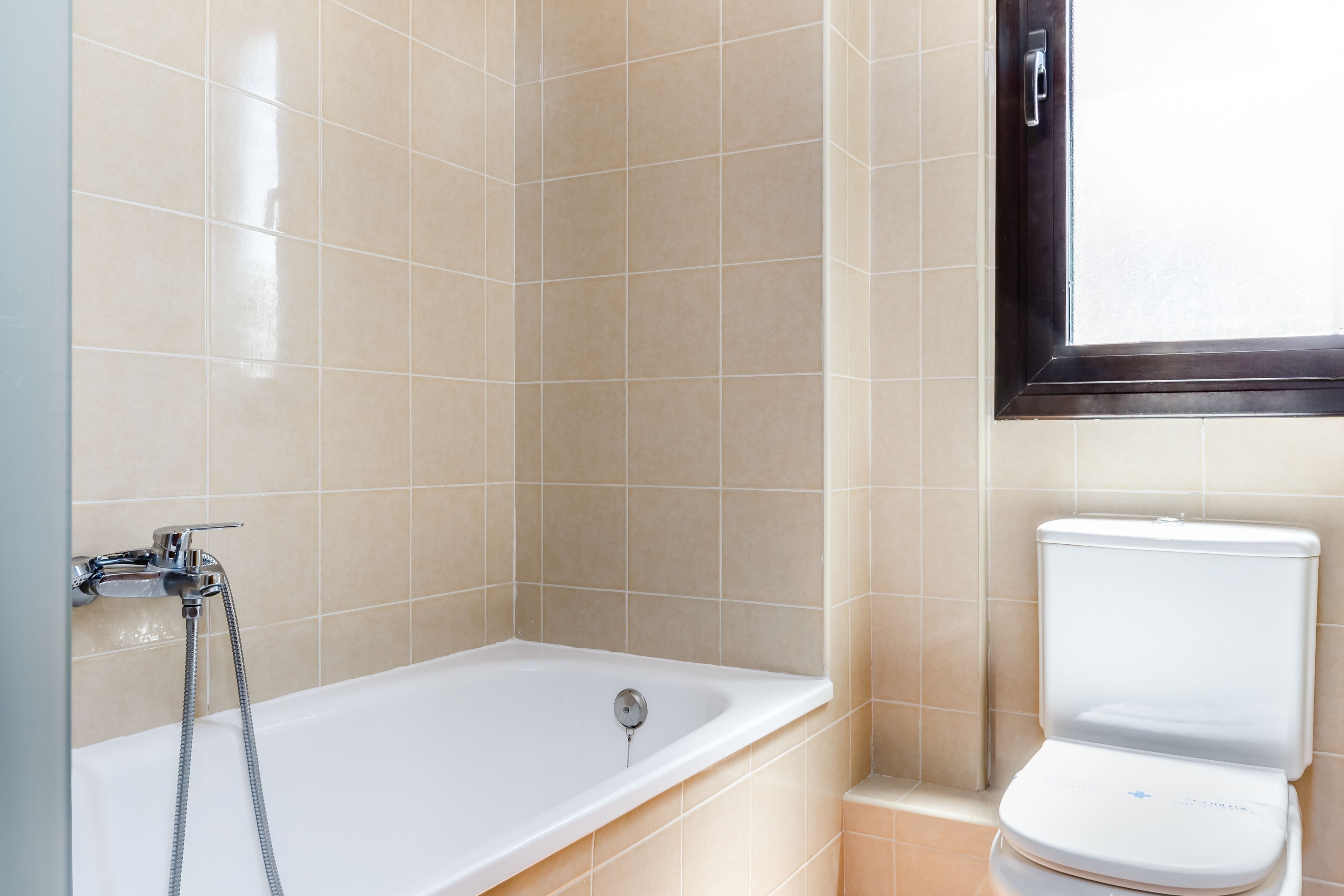 A bathroom with a bathtub, a toilet, and a window.