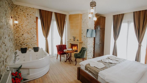 A hotel room with a large bed, a sitting area with a fireplace, and a separate bathtub.