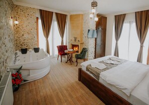 A hotel room with a large bed, a sitting area with a fireplace, and a separate bathtub. - Sea House Hotel (Sile)