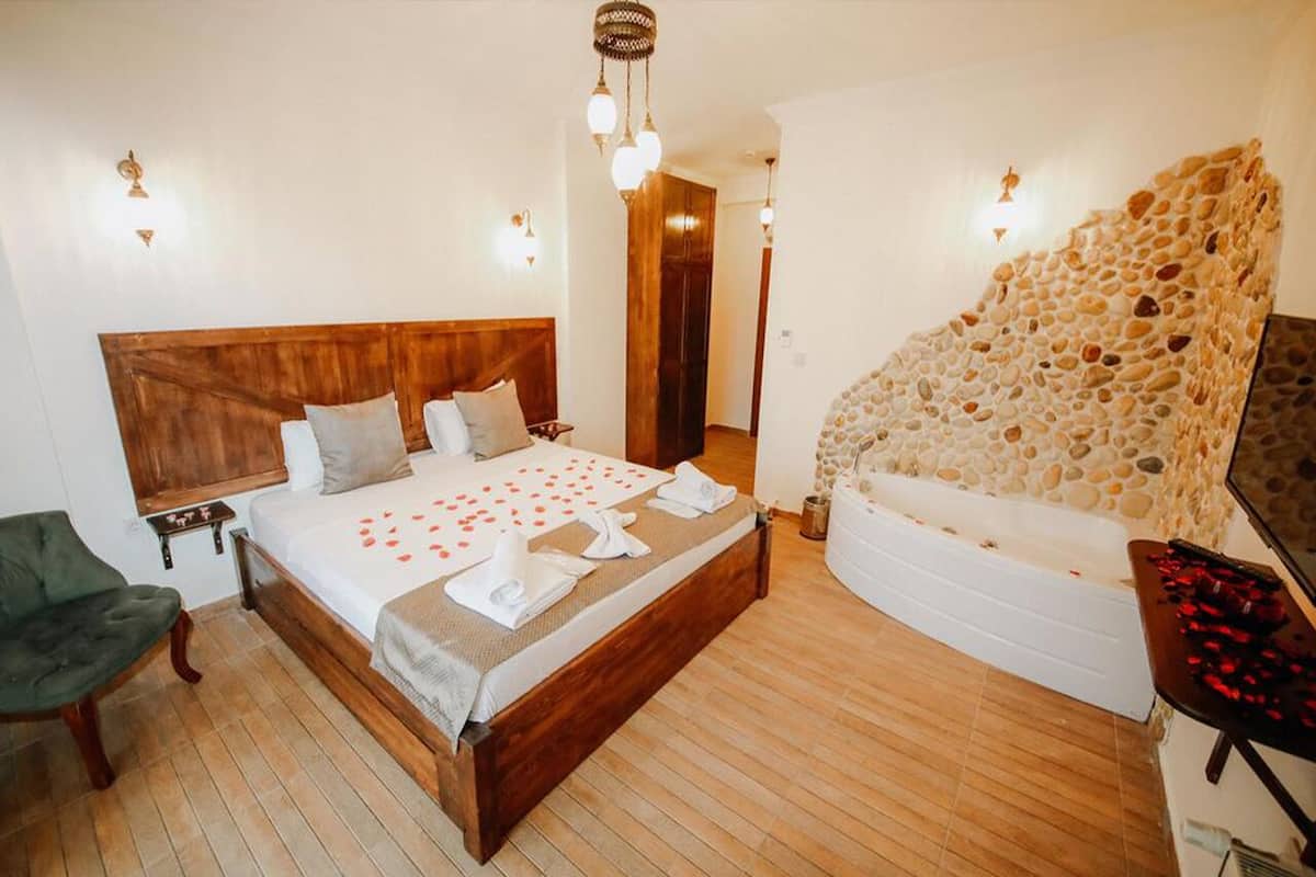 Un dormitorio con cama de madera, pared de piedra y una silla verde.