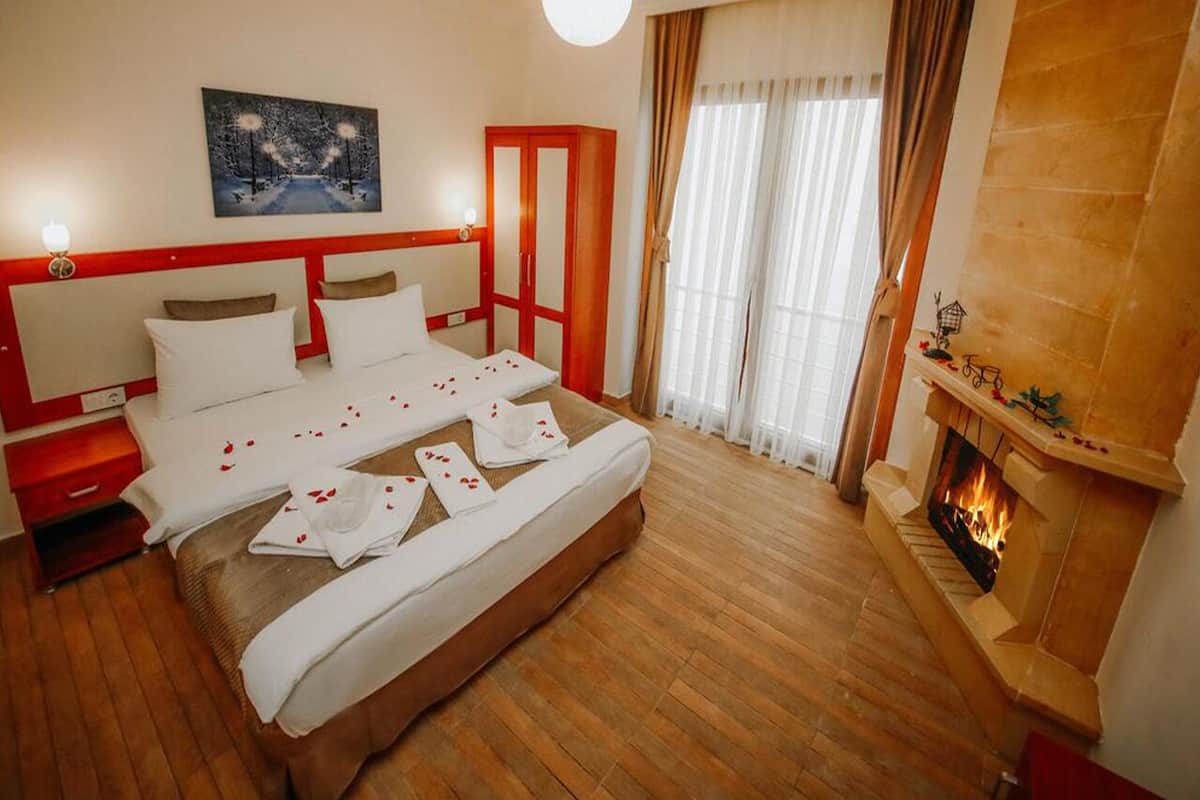 Una habitación de hotel con una cama, una chimenea y un cuadro en la pared.