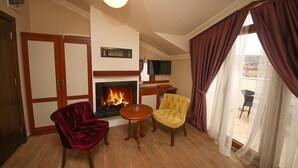 A living room with a fireplace, two chairs, a small table, and a television.