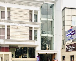 Een hotel met een moderne gevel, grote ramen en een standbeeld op het balkon.