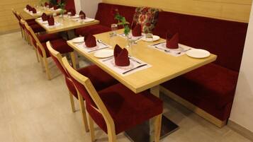 Un restaurante con varias mesas y asientos tapizados en rojo.