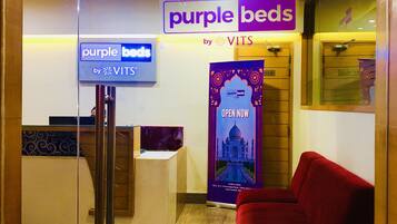 A reception area with a sign for 'Purple Beds by VITS' and a 'Purple Beds Open Now' poster.