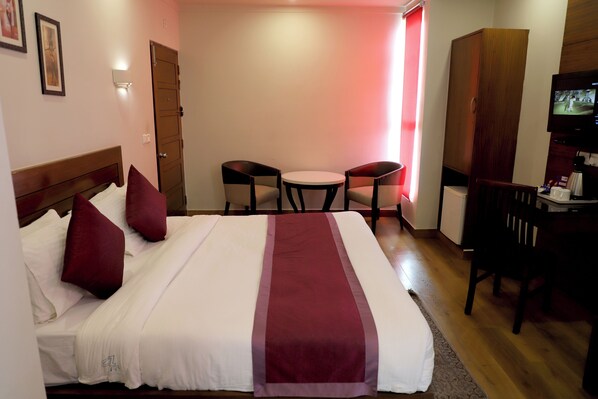 Een hotelkamer met een bed, twee stoelen, een bureau en een televisie.