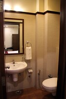 A bathroom with a sink, mirror, towel ring, and toilet.