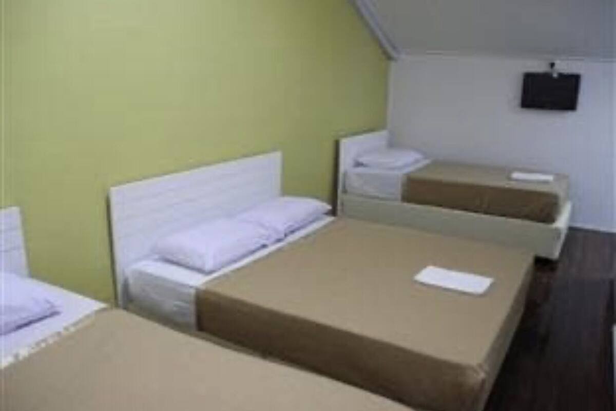 Une chambre avec deux lits simples, une petite table et un téléviseur fixé au mur.