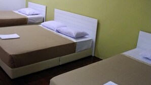 Ein Hotelzimmer mit zwei Betten, jeweils mit weißem Kopfteil und brauner Matratzenauflage. An der Wand über den Betten ist eine weiße Klimaanlage angebracht.