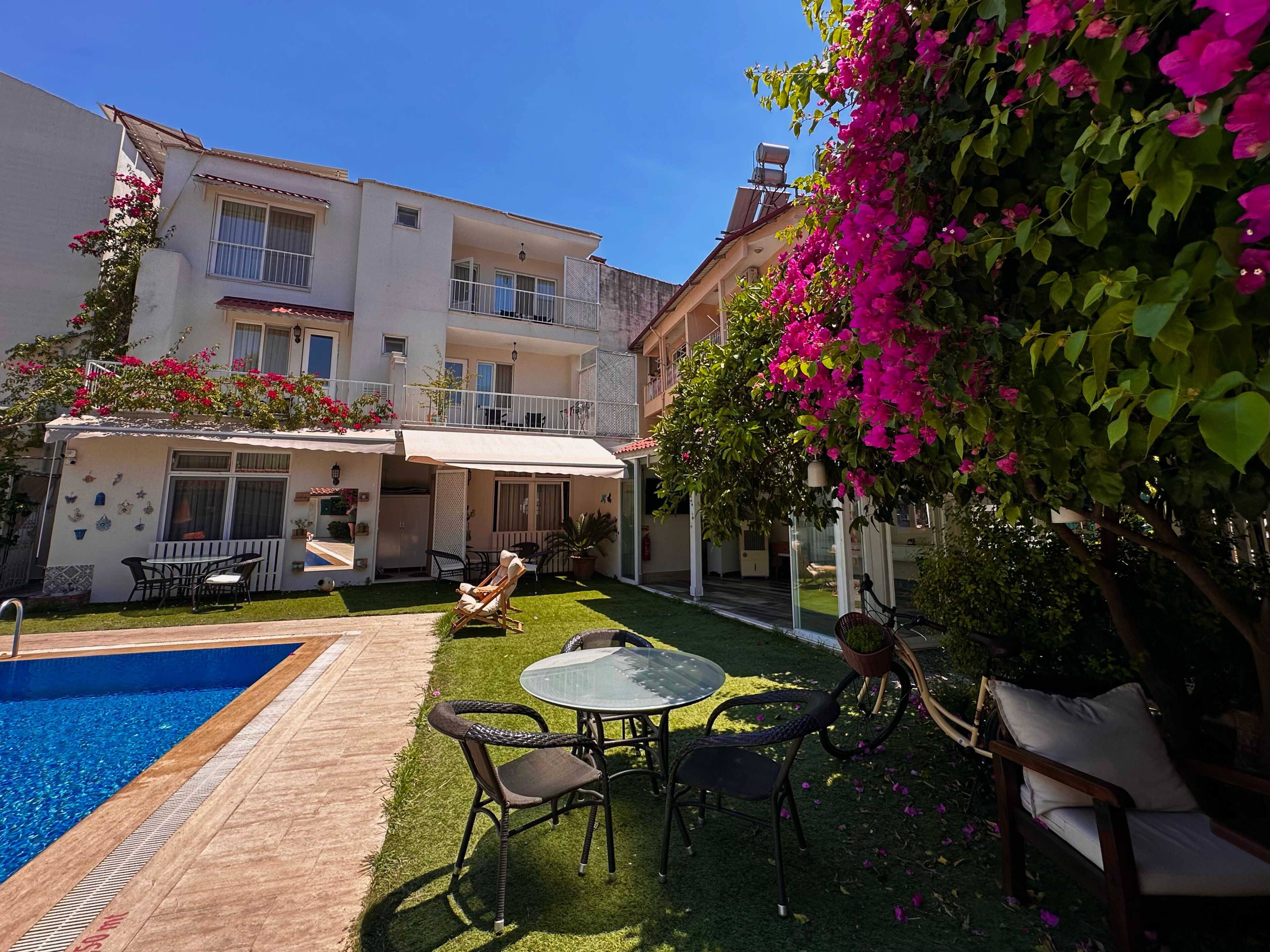 A residential building with a swimming pool, outdoor seating, and a balcony.