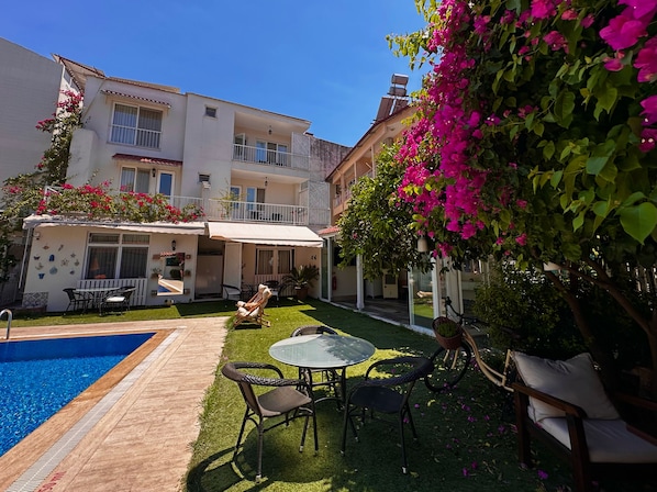 A residential building with a swimming pool, outdoor seating, and a balcony.