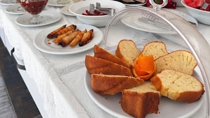 Une table de buffet proposant une variété d’aliments, notamment du pain, des pâtisseries et des fruits.