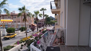 Un balcon donnant sur une rue, des palmiers et un taxi jaune.