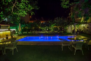 Una piscina al aire libre, sillones reclinables de piscina