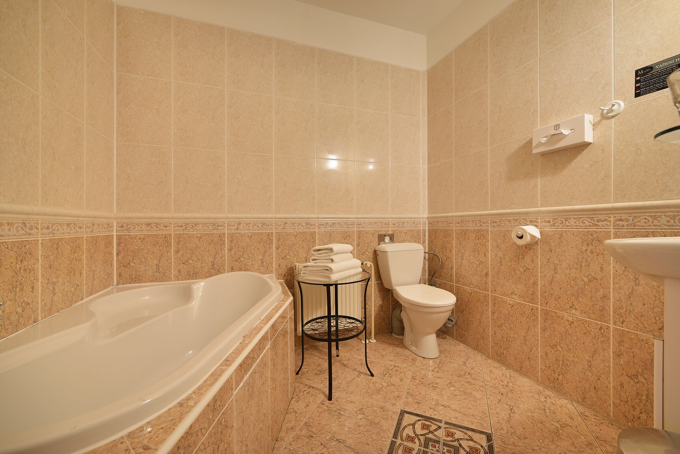 A bathroom with a bathtub, toilet, and a small table with towels.