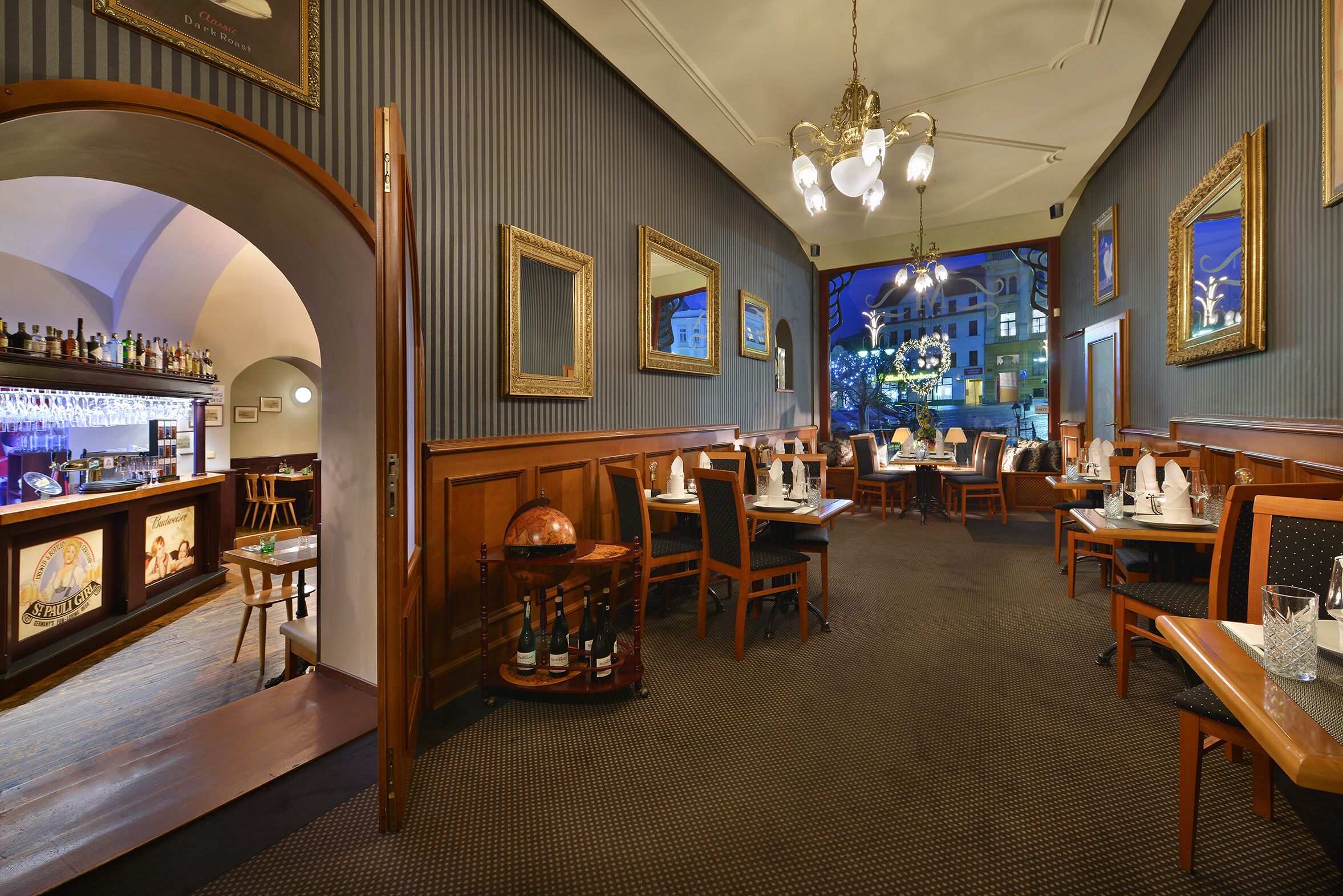 A restaurant with a bar area, wooden furniture, and framed pictures on the walls.