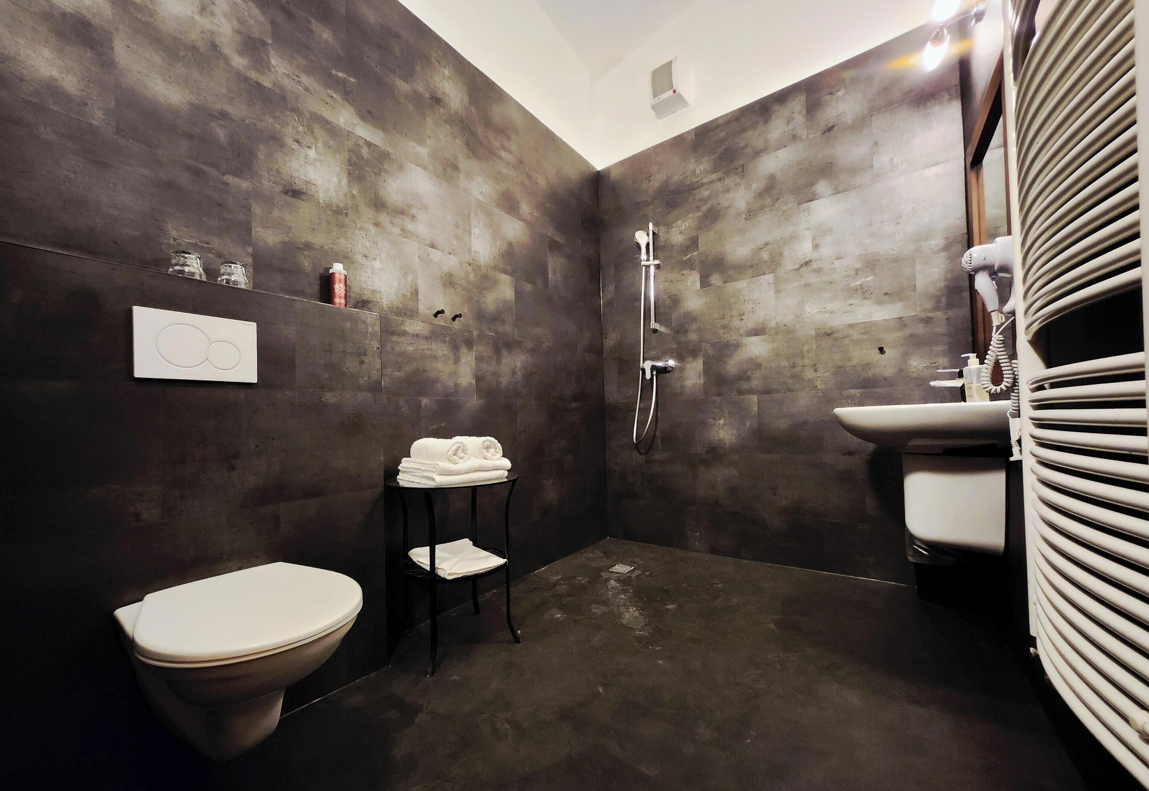 A bathroom with a toilet, a shower, a sink, and a towel rack.