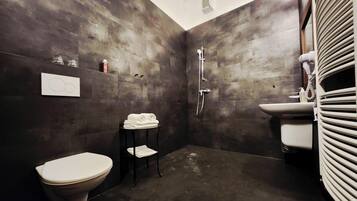 A bathroom with a toilet, a shower, a sink, and a towel rack.
