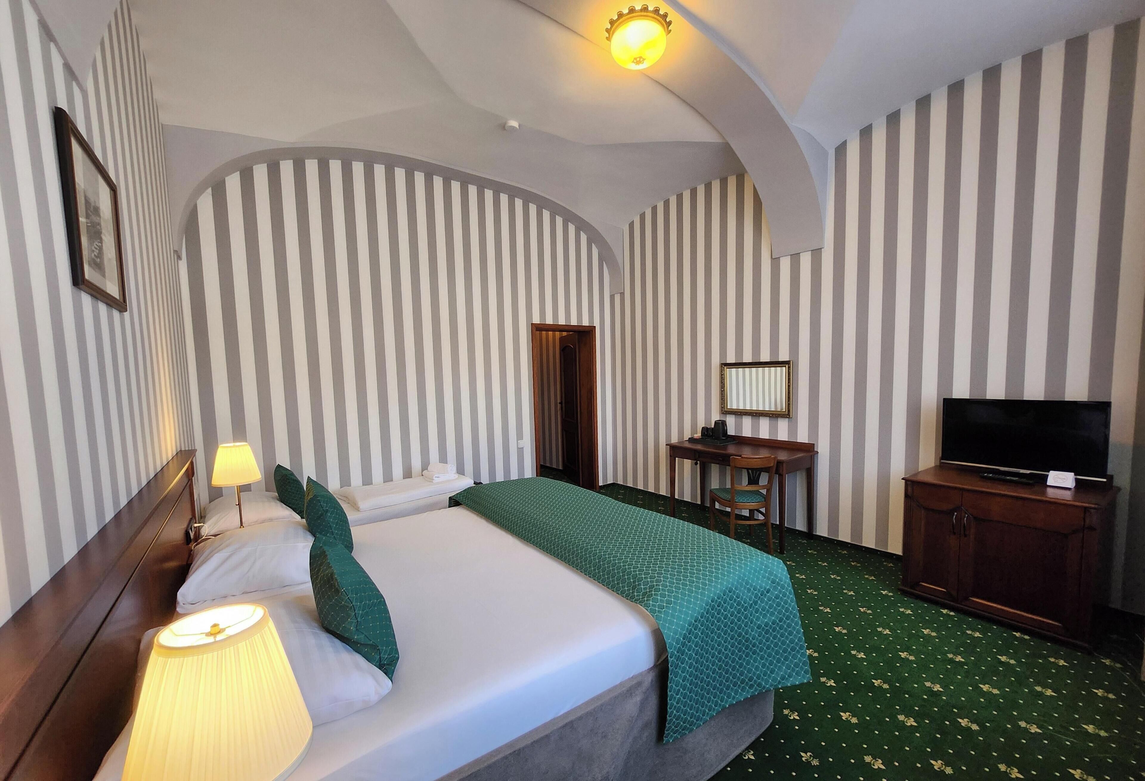 Une chambre d’hôtel avec un lit, un bureau, une télévision et un miroir.