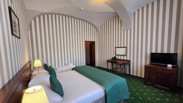 Une chambre d’hôtel avec un lit, un bureau, une télévision et un miroir.