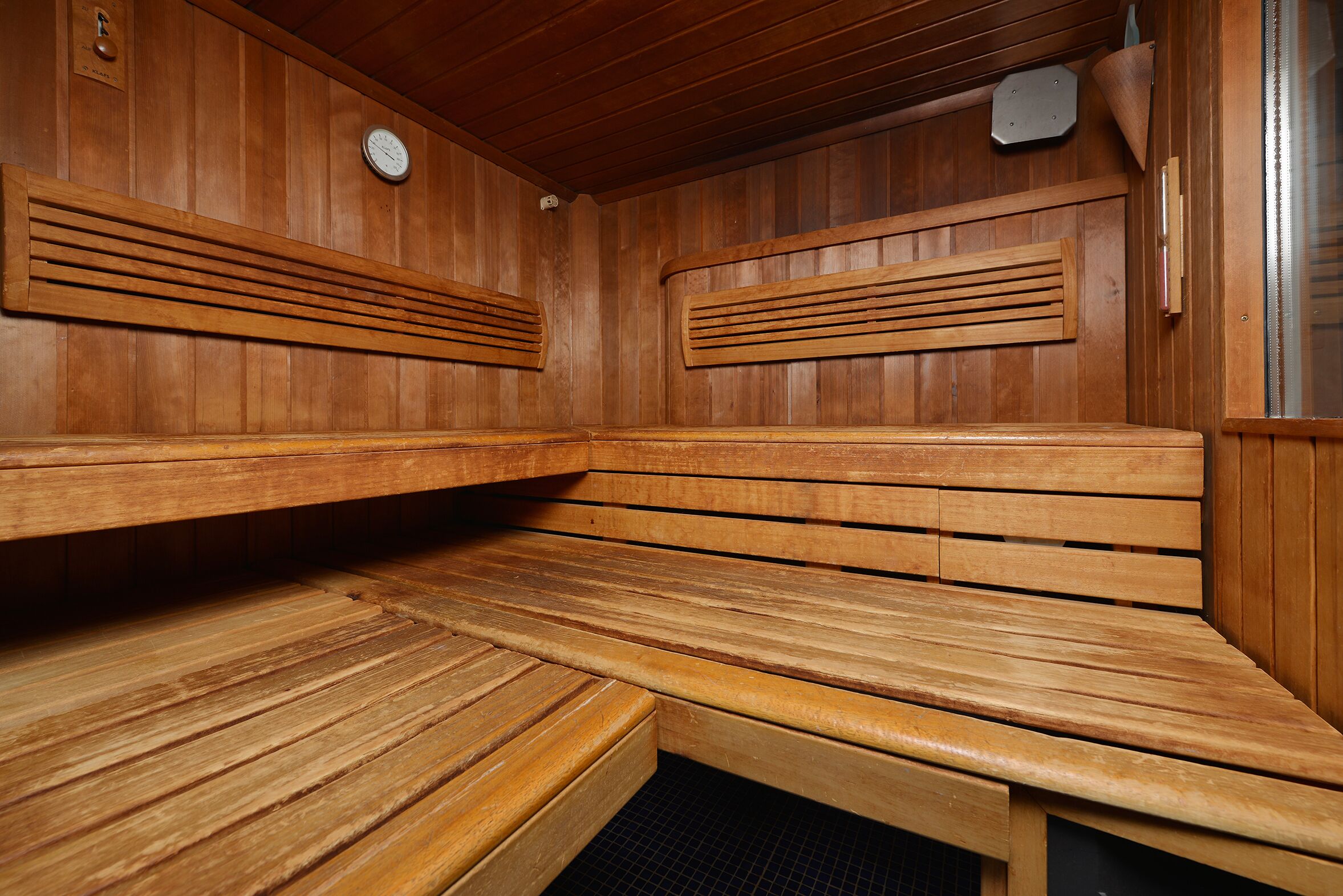 Una sauna de madera con bancos y un reloj en la pared.