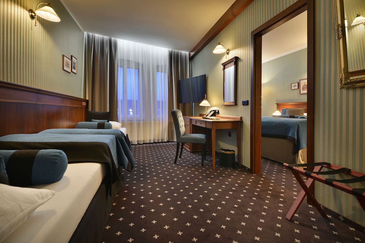 Een hotelkamer met twee bedden, een bureau, een stoel, een televisie en een spiegel.