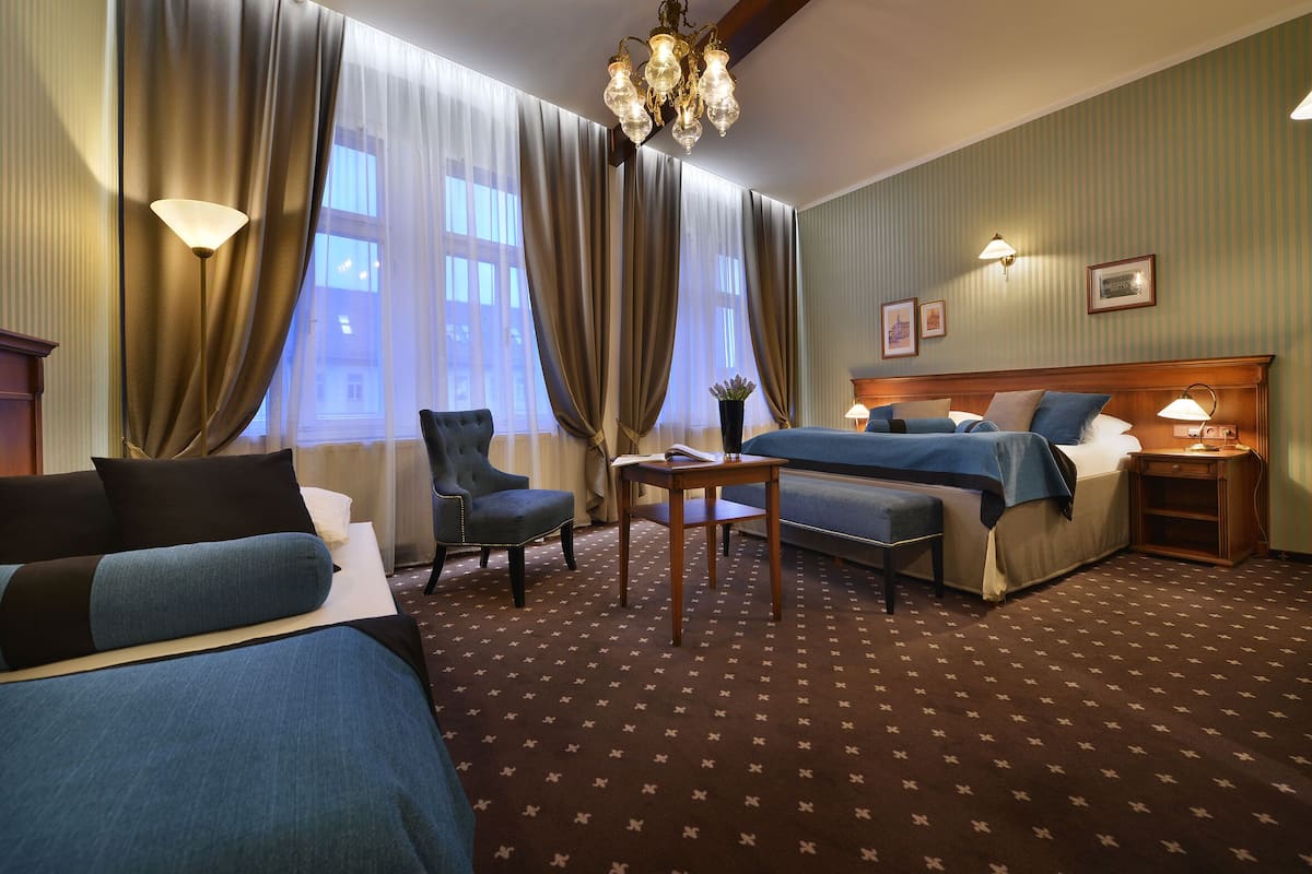 Een hotelkamer met twee bedden, een bureau, een stoel, een lamp en een kroonluchter.