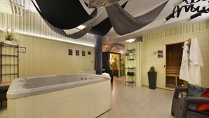 A spa area with a large hot tub, a seating area with a chair and a small table, and a wooden door leading to another room. - Parkhotel Morris Nový Bor (Novy Bor)