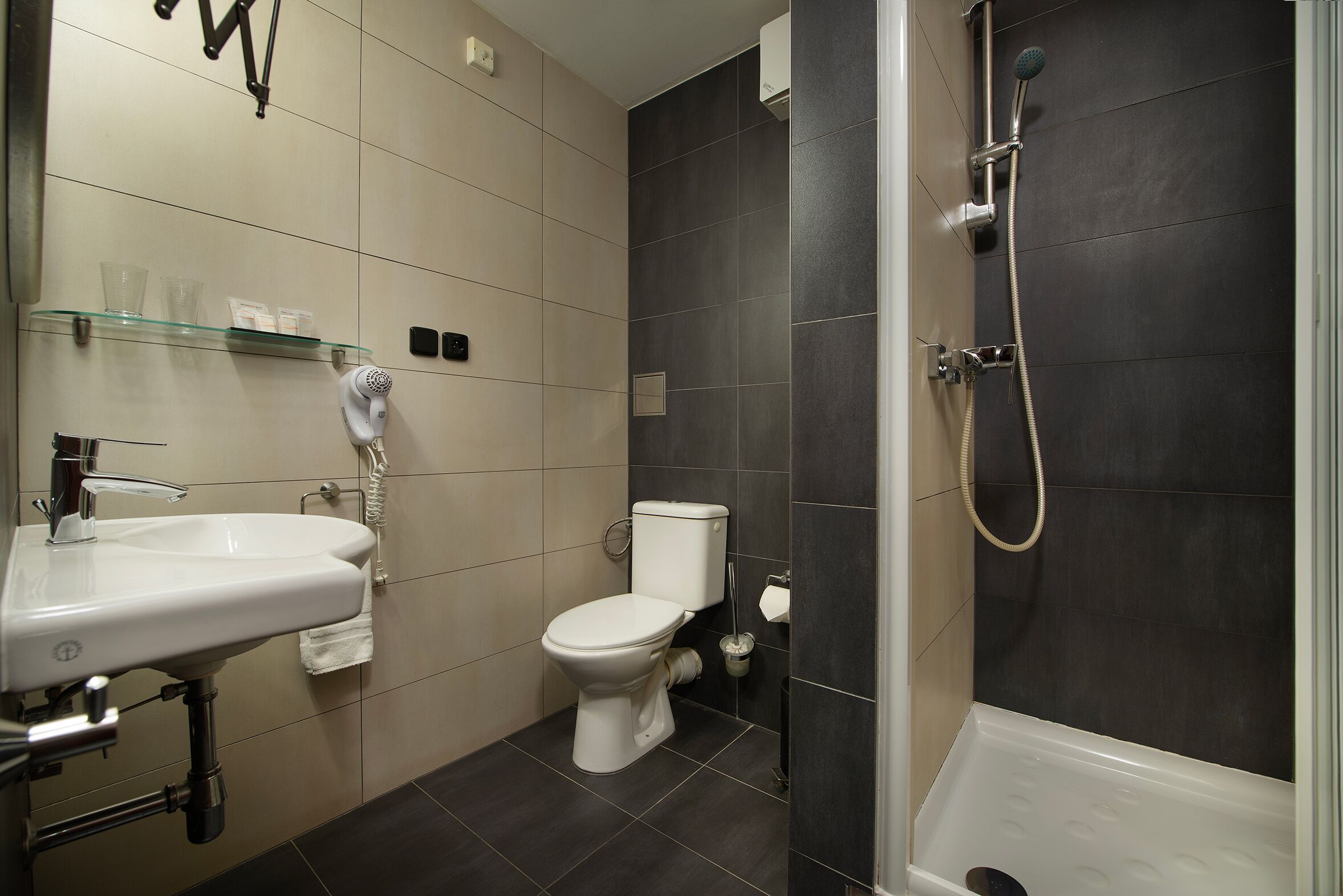 A modern bathroom with a white sink, toilet, and shower.