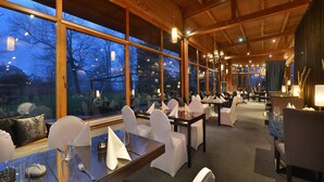 A restaurant with large windows, wooden beams, and white chairs. Tables are set with glassware and napkins. - Parkhotel Morris Nový Bor (Novy Bor)
