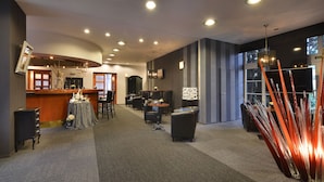 A modern hotel lobby with a reception desk, seating area, and decorative elements like a chandelier and a unique wall sculpture. - Parkhotel Morris Nový Bor (Novy Bor)