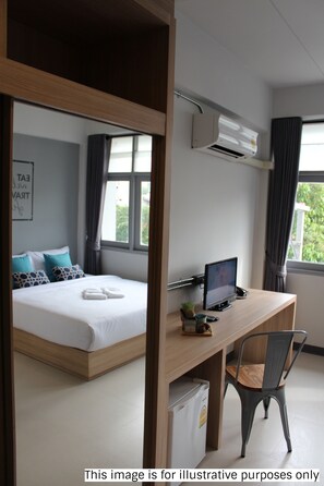 A bedroom with a bed, a desk with a computer, a chair, and an air conditioning unit.