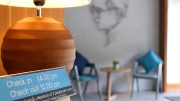 Señal de registro de entrada y salida con horarios: 14:00 y 12:00, y un máximo de dos personas por habitación.