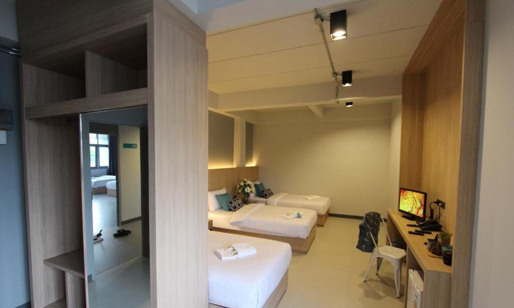 Una habitación de hotel con dos camas, un escritorio con ordenador y televisión.