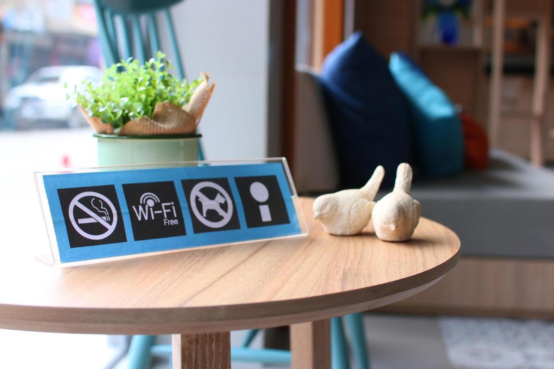 Une table avec un panneau indiquant qu’il est interdit de fumer, que le Wi-Fi est gratuit et que les animaux ne sont pas admis.