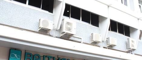 Un hotel con fachada moderna, amplias ventanas y unidades de aire acondicionado.